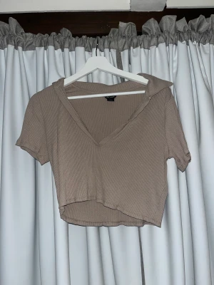 Topp med krage - Super söt croppad top i fin beige färg. Krage och V-ringning som gör stilen så fin😊Bara använd 2 gånger så i princip i nyskick. Storlek L men lite mindre i storleken💕