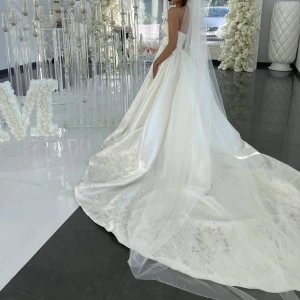 Bröllopsklänning i satin - Bröllopsklänning i satin med spets längs nedre kant på klänningen. Slöja medföljer på 3m.  Klänningen är o storlek 38, insydd till 32/34. Går att göra om till 38 om så önskas.  Köpt på Stockholm brud och fest