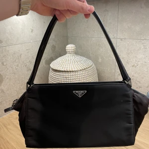 Prada Handväska - Prada handväska  Nylon Modellnummer: B11095 Färg: Svart Material: Nylon/läder Mått:  W32 × H18.5 × D7cm  Väldigt fräsch. Certifikat ingår. Billigare vid snabb och smidig affär. Finns på Östermalm i Stockholm. Kan givetvis skickas.
