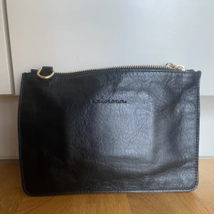 Clutch  - Svart liten clutch från Ulrika, finns inget band till. Äkta skinn. Inuti finns korthållare och ett sidofack med dragkedja. Helt oanvänd.