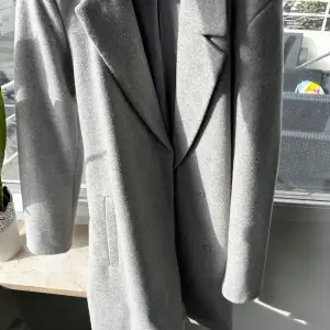 En väldigt fin grå kappa som är från villa. Den är nästan helt ny den är då i ett väldigt bra skick.