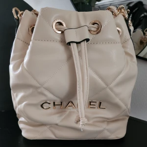 Beige cc bucket ( ej äkta)  - Säljer en beige cc bucket ( ej äkta , finns några små mörka närken på axelbandet , har aldrig anvönt den bara blivit ståendes sen köp 490:- pp