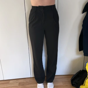 Svarta kostymbyxor  - Svarta, vida, långa kostymbyxor i storlek 34. Från NA-KD Selma Omari. Modellen bär vanligtvis storlek 36 och är 168 cm lång.