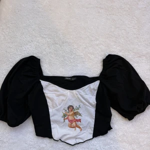 Svart topp med tryck - Svart topp med tryck som jag säljer, då jag inte tycker att den passar på mig. Passar stl xxs-m. 