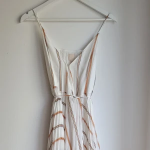 Flowy sommarklänning med omlottsnörning - Maxiklänning med tunna axelband och omlottsnörning i midjan. Andvänd ett fåtal gånger. 