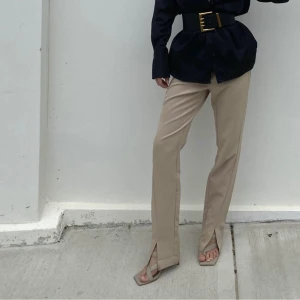 Kostymbyxor med slits  - Beiga kostymbyxor med slits fram ifrån NA-KD, storlek 38. Aldrig använda, är i nyskick. Köparen står för frakten. 