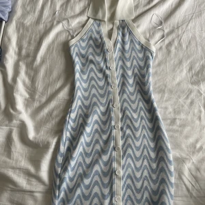 Klänning - Snygg blå och vit klänning i 50-tal tema. Djup rygg där bak! Storlek XS och aldrig använts.