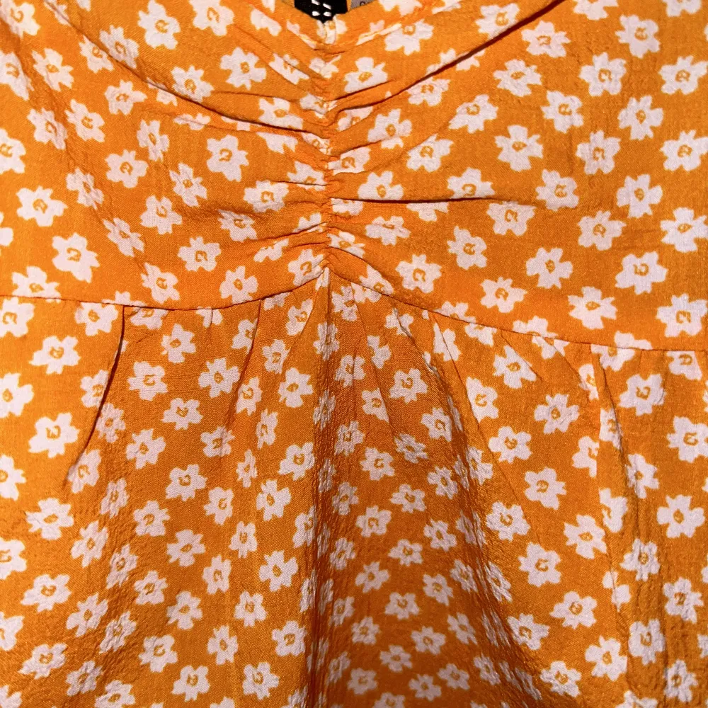 Säljer denna super söta orangea klänning med vita blommor. Klänningen är i xs och den har nu blivit för kort för mig💞✨  Den kommer ifrån divided - HM. Dragkedja på sidan och ihopdraget mellan brösten👌🏼✨💞. Klänningar.