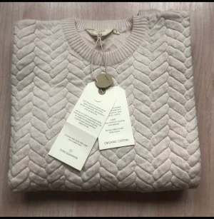 Tröja ny med prislappen kvar  - Tröja med fiskbensmönster jacquardmönster och ribbade kanter är en klassisk och elegant tröja som passar till både vardag och en festligare tillställning.  Från Basic Apparel Scandinavia Ekologisk bomull