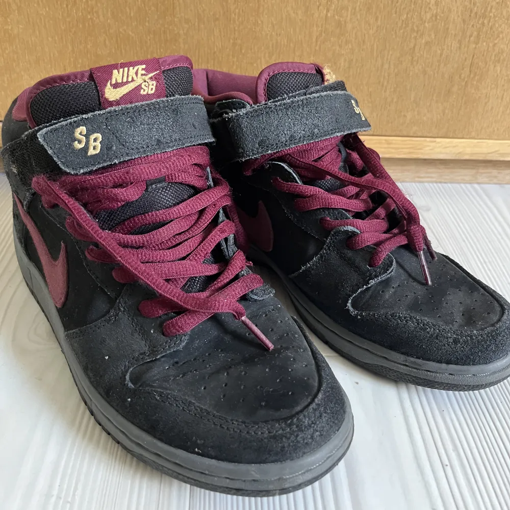 Nike SB Dunk Mid!! Säljer ett par riktigt snygga Nike SB Dunk Mid  Black Ostrich Cherrywood  skorna är i fint skick och har inga tydliga defekter.  Har tyvär inte kvar original lådan! Köparen står för frakt!. Skor.