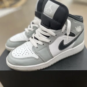 Jordan 1 mid - Air Jordan 1 Mid Light Smoke Grey Anthracite (GS) Skorna kommer med orginalåda. Innesula saknas. Inköpta 2022 välskötta, skick - 8,5/10 Två små sprickor i lädret, något slitna undertill annars perfekt skick.