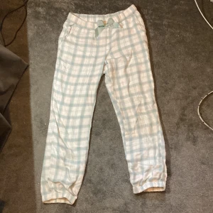 Pyjamas byxor  - Vit blå rutiga byxor med rosett fram. i fint skick. Använt noll gånger. 