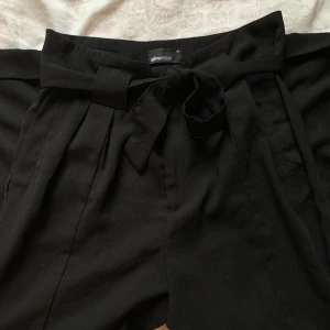 Kostymbyxor - Svarta kostymbyxor i skönt material med knytband från Gina Tricot. Saknar en knapp som inte gör någon större skillnad. Annars i fint skick! Säljs då de är för små🌼