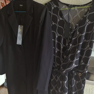 Nya ! Jumsuit + lång kavaj, Bubbleroom, Molly Rustas - 2 fina Nya plagg med lappen kvar. Har inte blivit använd pga fel storlek.  v ringad Jumsuit med sid fickor Happy Holly. Stl 40/42  Svart lång kavaj Dolda tryckknapppar- Molly Rustas for Bubbleroom, Längd ca 87 cm, stl 42.