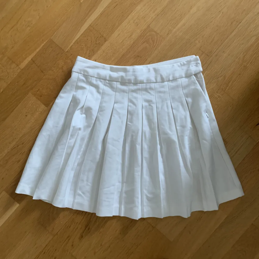 En vit kjol från New Yorker med volang. Stängs med dragkedja och en knapp på sidan. Kort i modellen och i ett mycket bra skick.. Kjolar.