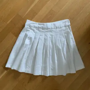 En vit kjol från New Yorker med volang. Stängs med dragkedja och en knapp på sidan. Kort i modellen och i ett mycket bra skick.
