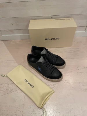 Axel Arigato skor -  Fina axel Arigato skor i bra skick använd ett tag men fortfarande riktigt stiliga, säljer PGA att de blev för små. Box och påse som du ser på bilden följer med.  Nypris: 2500kr Mitt pris: 899kr