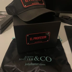 El Profesor keps - Säljer min keps nu för jag inte använder den längre. Väldigt fint skick, lite solblekt men inte så man lägger märke till det.  Köpt från Johnhatter.com  Låda plus bagen följer med. Nypris: 999kr Mitt pris: 299kr One size Köparen står för frakten.