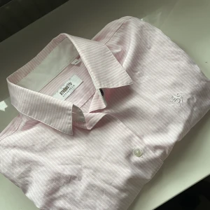 Rosa skjorta  - En rosa skjorta med smala vita ränder. Den är nästan helt oanvänd. Den passar perfekt till att ha på sig bara så men det blir även jättefin under en vit stickad tröja💓skriv för fler bilder 