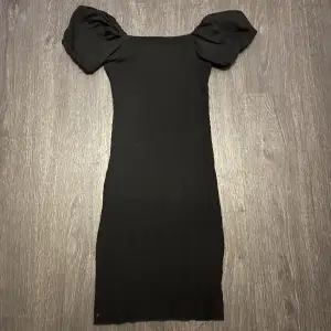 En tight, svart klänning med puffärmar med stretchigt material! 