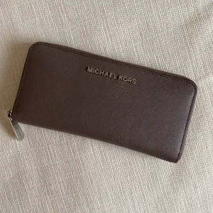 Michael Kors Plånbok - En rymlig Michael kors plånbok med flera kortfack och större fack. Använder inte. Grå/grön färg. Toppenskick!  