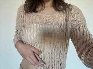 Skitsnygg nät-tröja från Gina tricot. Den är beige och jag har en vit topp under. Det är trekvarts ärmar. 