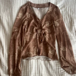 Indie blus - Jätte fin mönstrad blus som har ett gebelmskinligt material förutom runt bysten där den är dubbelfodrad. Ärmarna är utsvängda och det finns även en knytning under bysten 