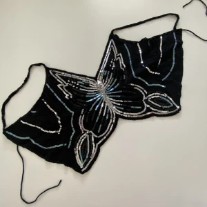 Fjärilstopp utan rygg - Jätte gullig topp utan rygg med blå och silvriga paljetter i form av en fjäril! Man knyter den med två band baktill. Storlek 38 men går att knyta till mindre storlekar!💕