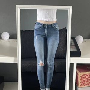 Midwaist Jeans - Jeans med hål vid knät och slitningar nertill.