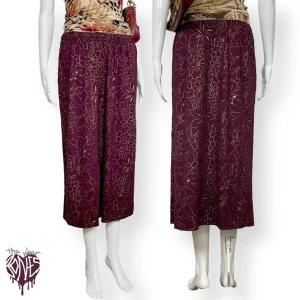 Kjol - Vinröd kjol med glittrande guldblommor. Ingen storlek eller materialetikett. Stretchband! Lite glitter kan falla av då och då under användning. ⚠️ Mått liggandes: Midjebredd 36,5 cm (räkna det som höftvidd för en lågmidjad passform) Längd 80cm