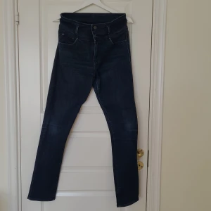 Blå stretchjeans - Blå stretchjeans i stl 36N (normal) från Flash i modell Dolly. Hög i midjan med blixtlås och 3 knappar. 