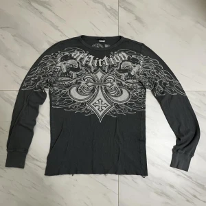 AFFLICTION LÅNGÄRMAD TRÖJA - Använt skick, inga fläckar eller skador; bara lite sliten där nere. Sitter jättebra vid magen så hänger inte bara på axlarna som ett lakan.  