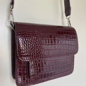 Hvisk axelrämsväska mörkröd/bordeaux - Hvisk väska i mörkröd/bordeuax färg, i gott men använt skick. Spännerna har inga tecken på rost eller missförgning likaså är lädret intakt. Ca 699kr nypris. Kan mötas upp i Göteborgsområdet annars står du själv för frakten. 