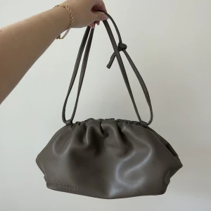 Brun väska - Brun väska från k cobler! Går att ljustera banden genom att knyta på olika sätt! Använd men i nyskick!