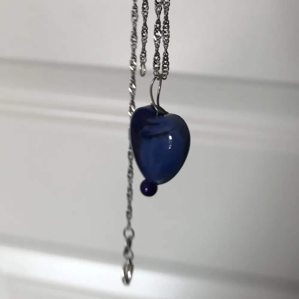 Blått halsbandshänge av ett blått glashjärta och fossil sten. Nytt oanvänt och handgjort. Har också andra smycken på min profil🌺. Accessoarer.
