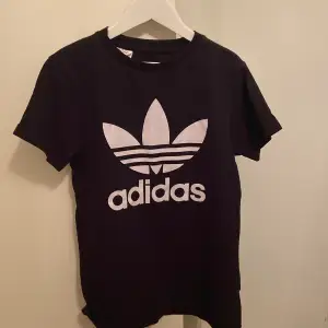 En Adidas t-shirt! Den är svart med en vit text där det står Adidas. Ett bra skick!