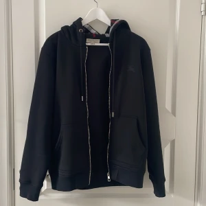 Äkta Burburry Zip hoddie Stl M - Burburry Zip hoddie i Nyskick. Endast använd fåtal gånger. Tags fås med. Nypris 6000kr 