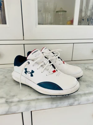 Golfskor Strl 37,5 Under Armour FRI FRAKT  - Storlek 37,5  22.5 cm Använda av ett barn 3 gånger. Något små i storleken, framför allt när fötter blir varma under 18 hål. Fint skick även om lite skav, kommer direkt på vita skor och i gräs. Sula är nyskick och fräscha inuti, ingen lukt. Dyra i inköp 