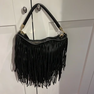 Fransig väska - Fin svart väska med fransar från hm. Går att bära både över axeln och crossbody. 