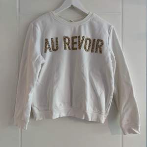 Vit hoodie (utan luva) från H&M med ’Au revoir’ print i form av guldiga och vita pärlor. 