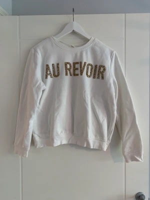 Vit hoodie - Vit hoodie (utan luva) från H&M med ’Au revoir’ print i form av guldiga och vita pärlor. 