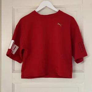 Röd T-shirt - En kortare T-shirt med lite längre ärmar från Puma. Använd ett fåtal gånger, bra skick. Säljer eftersom den inte kommer till användning. 
