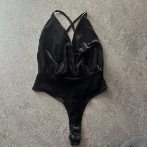 Body XS - Sammets body med djup urringning och korsning i ryggen. Svart Rebecca Stella Storlek: XS/34  Använd fåtal gånger, fint skick! 