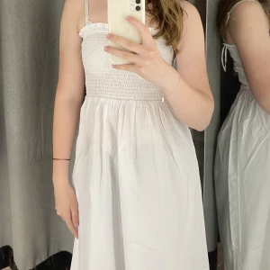 Klänning - Oanvänd vit klänning med prislappen kvar. Man kan välja att ha den med eller utan axelband då de är avtagbara. Perfekt till student eller midsommar! Skriv vid frågor