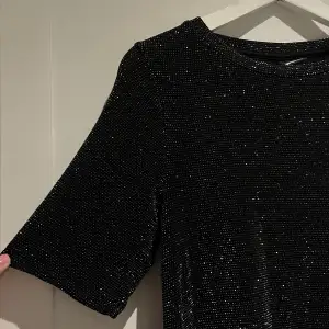 Svart glittrig klänning från gina tricot i t-shirtmodell, helt oanvänd!