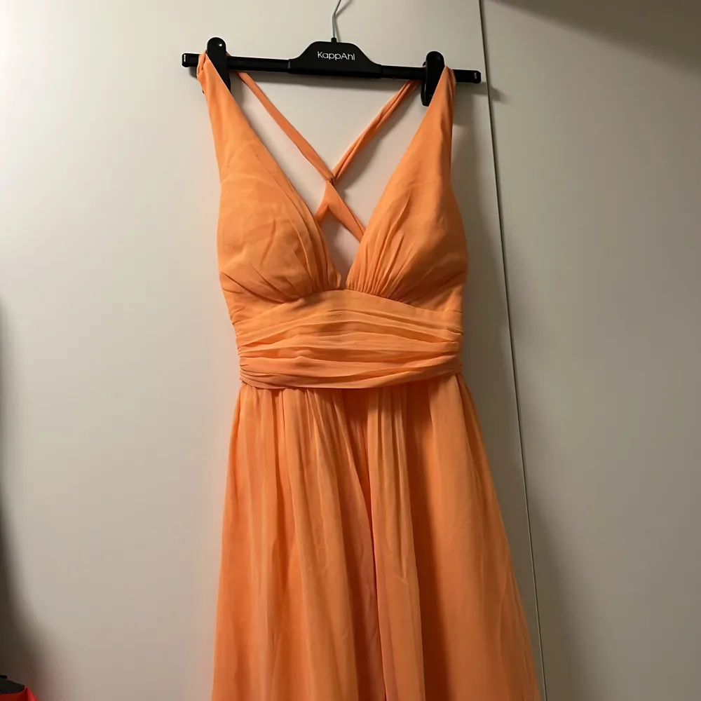 Balklänning från Nelly i färgen peach med korsad rygg. Använd 1 gång på bal. Vadderade bröst.  Klänningen är mer orangefärgad på bilden.. lite mildare åt rosa hållet i verkligheten. . Klänningar.