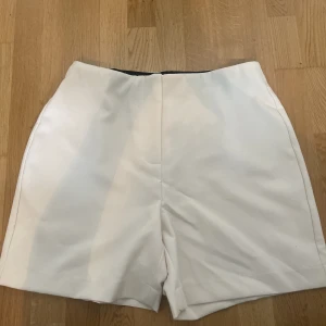 Vita/beiga vero moda shorts🤍 - Vita/beiga högmidjade tygshorts från Vero Moda. Aldrig använda pga fel storlek för mig. Lapparna bortklippta, passar som M. Kan skicka mått vid efterfrågan 🫶🏻 Köpta i butik för någon månad sen, finns inte längre på hemsidan.  Nypris ca 250-300kr