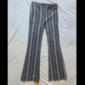 Gråa randiga bootcutbyxor - Gråa randiga bootcutbyxor som sitter tajt. Fina sommarbyxor som man kan ha skärp till. Kostymbyx aktiga.
