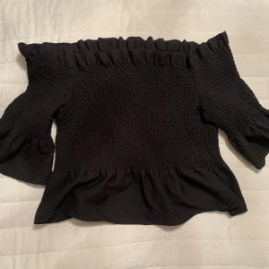 Off shoulder topp - Svart off shoulder topp med volanger, aldrig använd. I strl L 