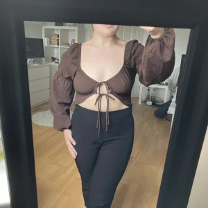 Topp - Brun topp med knyten vid bysten. Vid det översta snöret finns ett band som håller ihop toppen så det är ingen risk att den går upp. Aldrig använd då jag har liknande toppar.